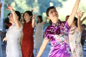 身着紫色旗袍、高举双臂起舞的舞友