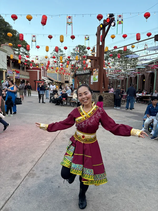 身着民族服装,在灯笼下张开双臂起舞
